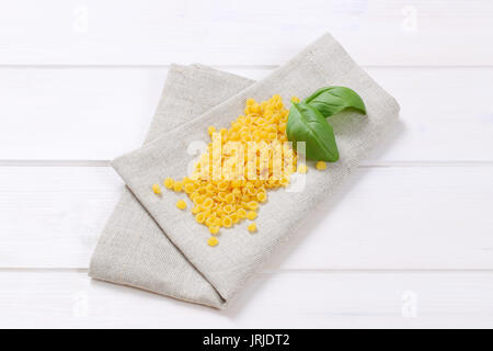 pile of small pasta shells on beige place mat Stock Photo