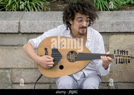 A Moroccan oud player performing ethnic music and soliciting donations in Union Square Park in Manhattan, New York City Stock Photo