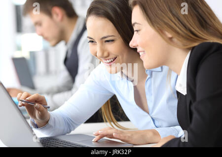 Two businesswomen working together on line with a laptop at office Stock Photo