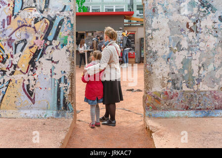 Mother and daughter, a parent and child  - mother and daughter - pose between two sections of the Berlin Wall in the Mauermuseum, Berlin,Germany Stock Photo