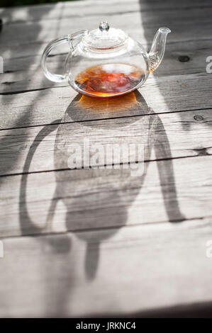 Traditional Chinese tea ceremony - Chinese glass teapot filled with red tea on wooden table Stock Photo