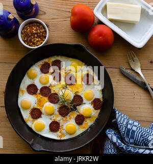 fried quail eggs with sausage in black pan Stock Photo