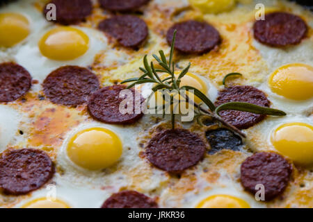 fried quail eggs with sausage in black pan Stock Photo