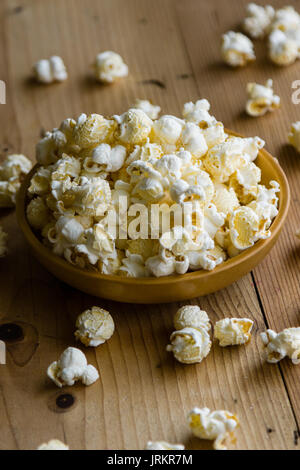 fresh salted popcorn in bowl on wooden table Stock Photo