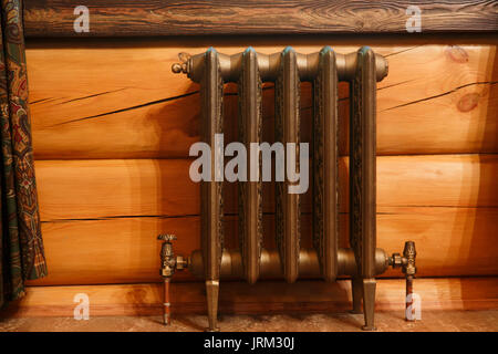Cast iron retro design radiator in timber house. Stock Photo