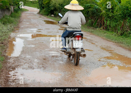 HAI DUONG, VIETNAM, September, 22: the unidentified man rides motorcycle on muddy road on September, 22, 2013 in Hai Duong, Vietnam Stock Photo