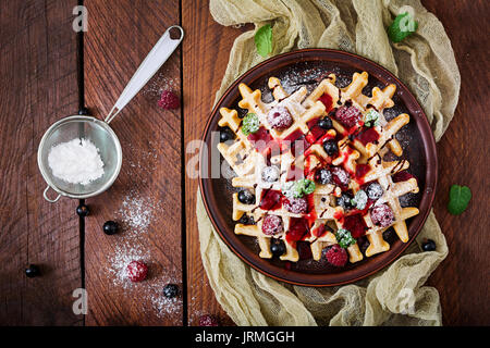 Belgium waffles with raspberries, chocolate and syrup on a plate. Stock Photo