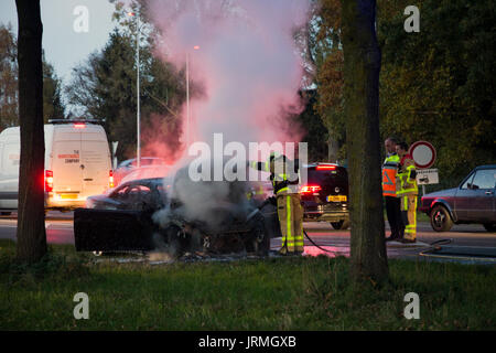 ACHTERHOEK, NETHERLANDS - OCT 29, 2015: Firefighters near a burned out car wreck. Stock Photo