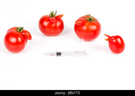 Tomatoes with deformation and defects, with syringe. Chemical treatment for rapid maturation in tomatoes. Strange forms grown mutated tomatoes. Front  Stock Photo