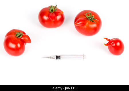 Tomatoes with deformation and defects, with syringe. Chemical treatment for rapid maturation in tomatoes. Strange forms grown mutated tomatoes. Front  Stock Photo