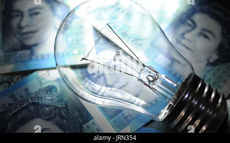ELECTRIC LIGHT BULB WITH BRITISH MONEY RE ENERGY PRICES ELECTRICITY SUPPLIERS RISING FUEL COSTS HOUSEHOLD BUDGETS UK Stock Photo
