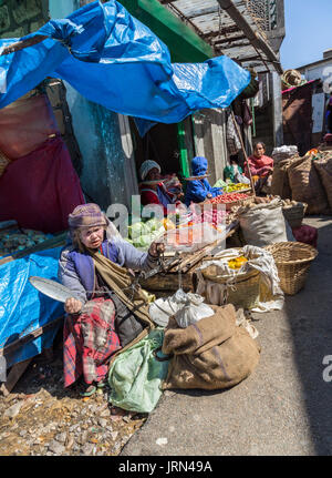 Woman in street market setting up stall holding scales, Mawsynram, Meghalaya, India Stock Photo