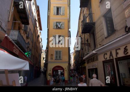 Tourists strolling in old town street with tall narrow apartment exterior, Nice, France Stock Photo