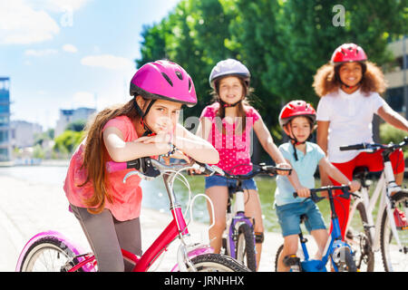 Portrait of 11-12 years old girl in pink safety helmet standing with bicycle and waiting for her friends Stock Photo