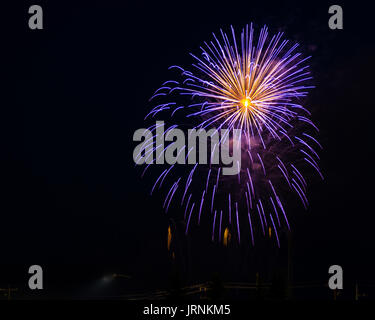 Fireworks display of bright blue and gold colors against a black background during an evening of celebration of a national holiday. Stock Photo