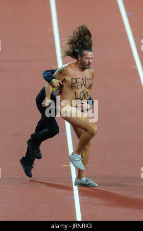 London, 2017 August 05. A security operative tackles a streaker with 'Peace + Love' written on his chest runs down the track at the IAAF World Championships London 2017. © Paul Davey/Alamy Live News Stock Photo