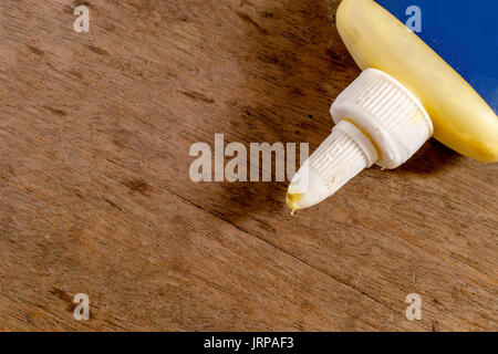 Wood glue with blank blue label on a wooden surface Stock Photo