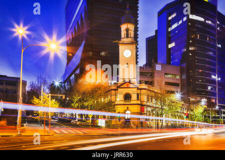 Historic heritage North Sydney post office building with clock tower against tall modern business high-rises at sunset on car traffic street. Stock Photo