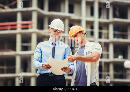 Architect and builder discussing at construction site Stock Photo