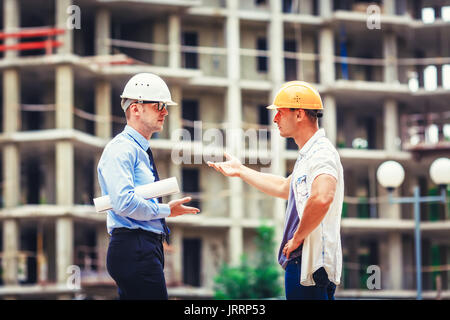 Architect and builder discussing at construction site Stock Photo