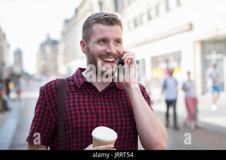 Man Walking Along City Street Talking On Mobile Phone Stock Photo