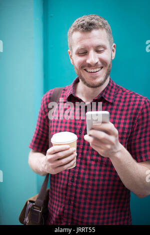 Man Standing In Front Of Blue Door Reading Text Message Stock Photo