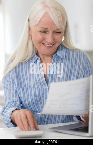 Smiling Mature Woman Reviewing Domestic Finances Stock Photo
