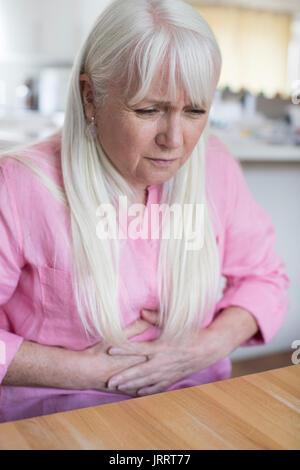 Mature Woman Suffering From Stomach Pain At Home Stock Photo