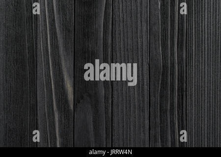 Black Wood Texture. Black stained wooden billboard close-up. Vertical direction cohesive boards. Wavy pattern of wood fibers Stock Photo