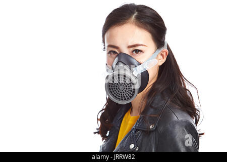 young asian woman in black leather jacket wearing a gas mask looking at camera, isolated on white background.