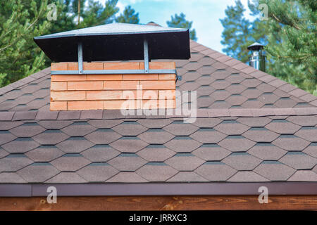 Modern roofing and decoration of chimneys. Flexible bitumen or slate shingles. Stock Photo