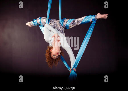 Aerialist woman doing some tricks on silks Stock Photo