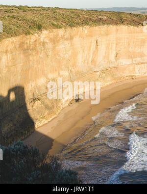 Tiny person in comparison to the cliffs of the Gibson steps of the Great Ocean Road in the golden light of dusk. Stock Photo