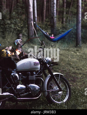 Hammock motorcycle camping with classic custom vintage motorbike and lady in hammock. Stock Photo