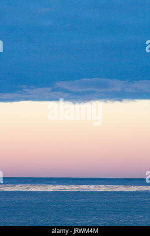 Atlantic ocean just after sunset with a pink sky and dark blue clouds over the horizon Stock Photo