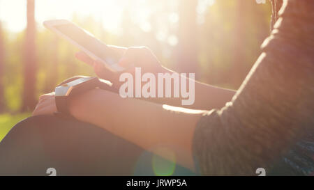 Lifestyle wearable technology shot with lensflare. Female athlete using fitness app on her smart watch to monitor workout performance Stock Photo