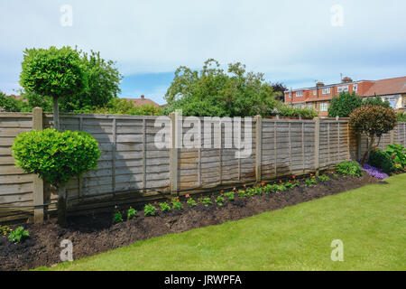 Flower bed with garden fence and lawn, taken in early summer. Stock Photo