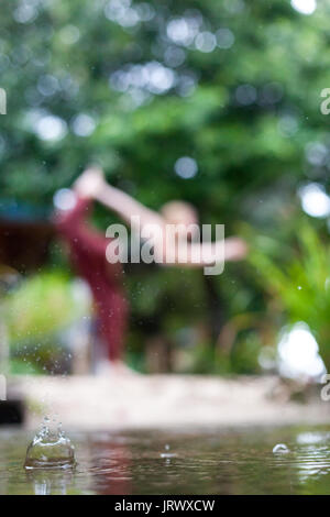 Connecting with mother nature by doing a yoga practice in the rain. Outdoors. Stock Photo