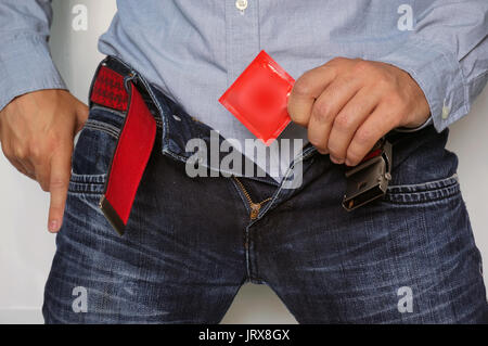 Cropped image of a man holding condom in hand while taking it from jeans. Stock Photo