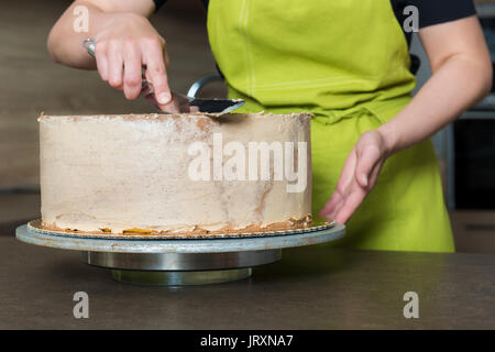 Unrecognisable woman decorating a delicious layered sponge cake with chocolate icing cream Stock Photo
