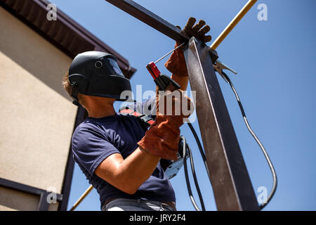 Man welding metal construction at his backyard. Stock Photo