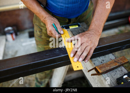 Man measuring off metal bar in workshop. Stock Photo