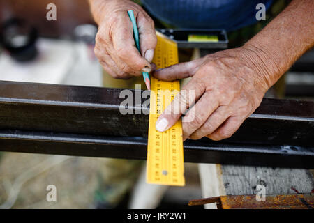 Man measuring off metal bar in workshop. Stock Photo