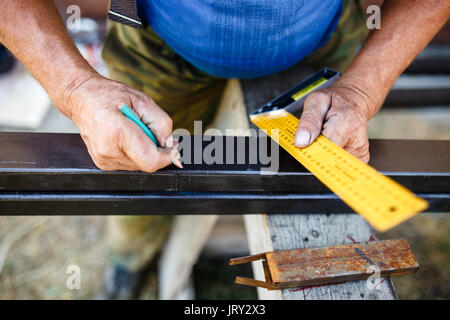 Man measuring off metal bar in workshop. Stock Photo