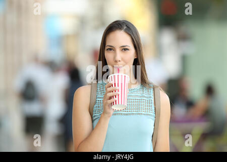 Front view of a girl sipping a takeaway drink walking on the street Stock Photo