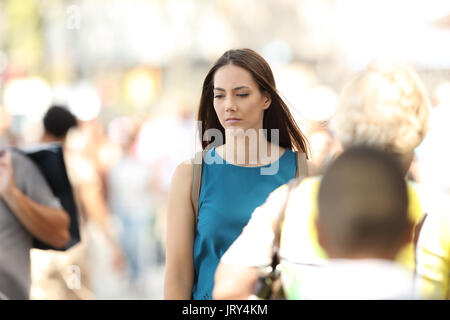Sad woman feeling alone walking between people on the street Stock Photo
