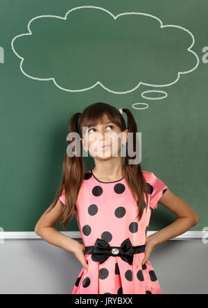 child near school blackboard with blank speech bubble Stock Photo