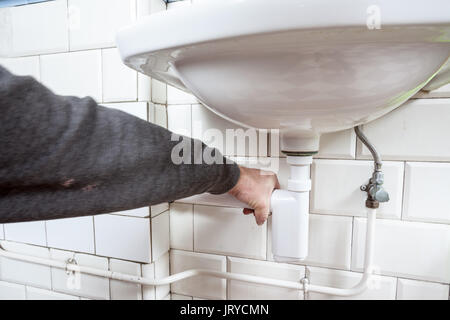 in an public restroom hangs on an wall of an white sink Stock Photo