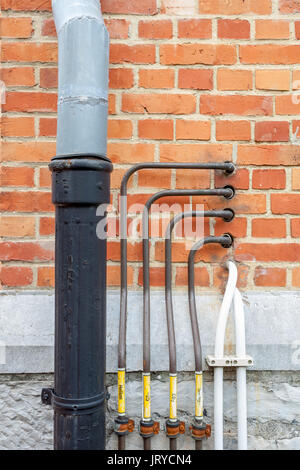 On the wall of a building there is a rain drain and copper pipes and an electricite wire Stock Photo