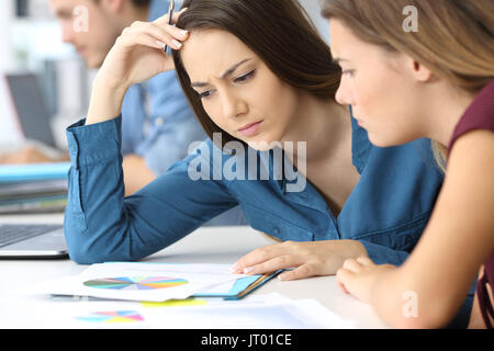 Two confused businesswomen checking paper documents at office Stock Photo